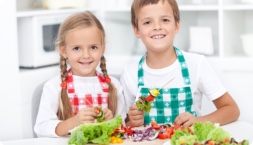 Two children with a plate of fresh vegetables