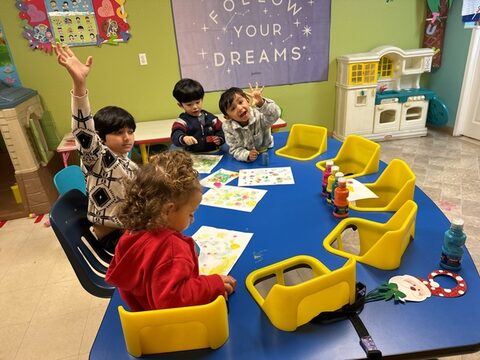 Children creating art together around a classroom table