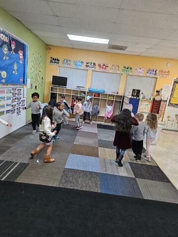 Children moving and playing together inside a bright classroom