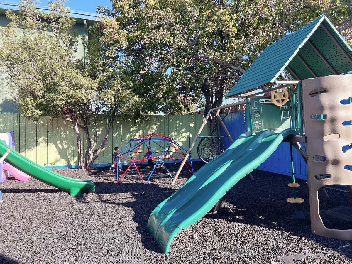 Wide view of the shaded outdoor play area and play structure